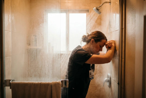Nurse under warm shower steam after shift decompression ritual
